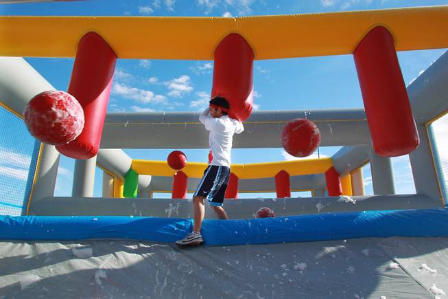 A participant makes his way across a sudsy bridge while balls are thrown at him during the Hit and Run 5k Saturday, March 1, 2014 at Sam Boyd Stadium. The Hit and Run 5k, a fun run with various obstacles to navigate, is being held or planned in two dozen cities across the country.